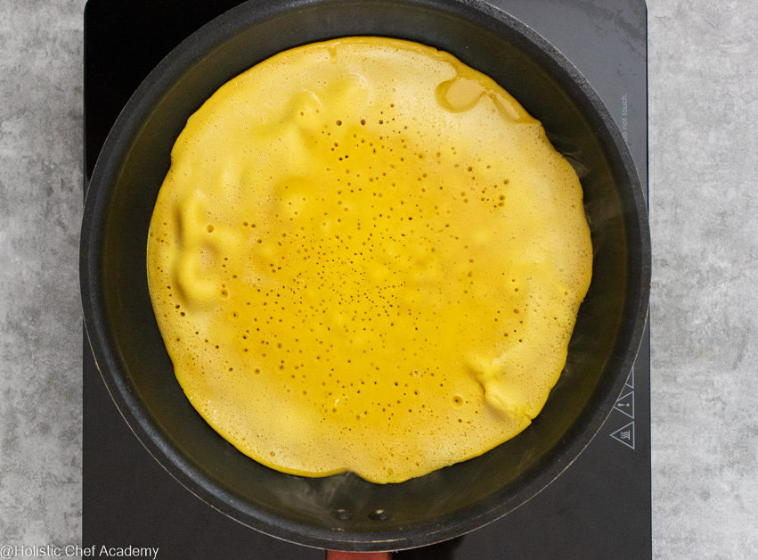 Cooking the chickpea socca flatbread in the frying pan