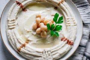 Transfer the hummus onto a plate, smooth it with the back of a spoon. Drizzle with extra virgin olive oil and a sprinkle of chili and cumin powder.