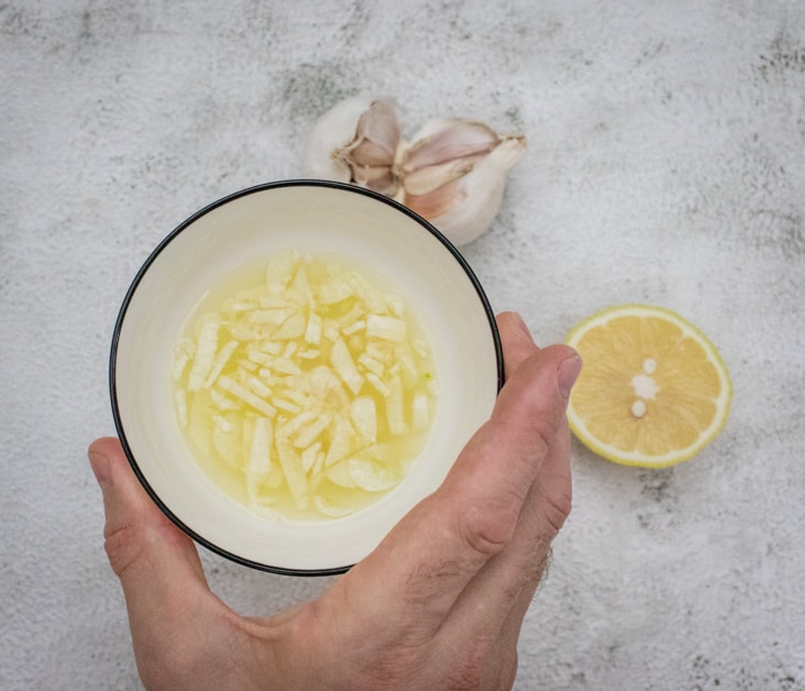 soaking slice garlic in lemon juice for making the perfect hummus