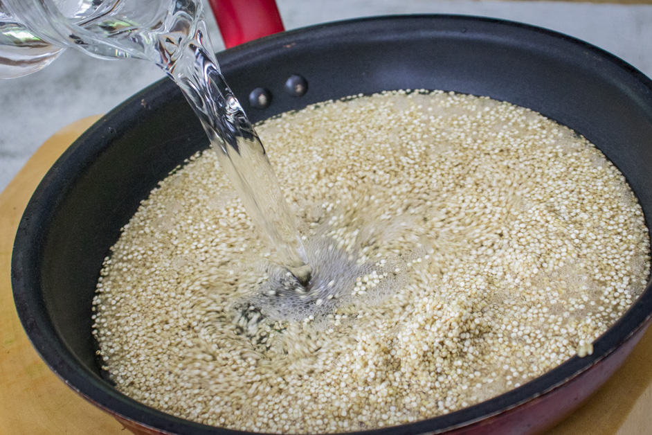 adding water to quinoa to cook