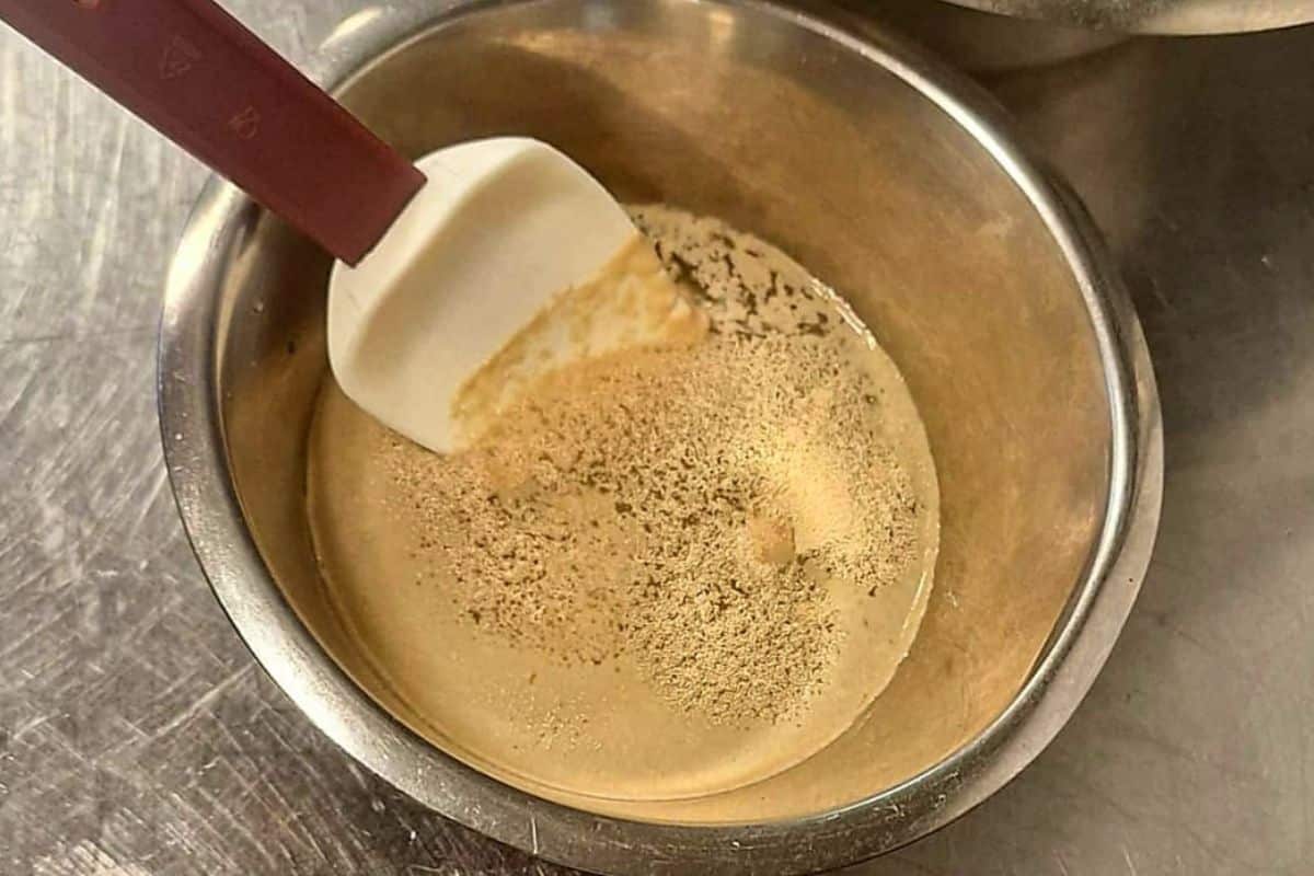 Bowl of warm water with sugar and yeast starting to foam for simit dough