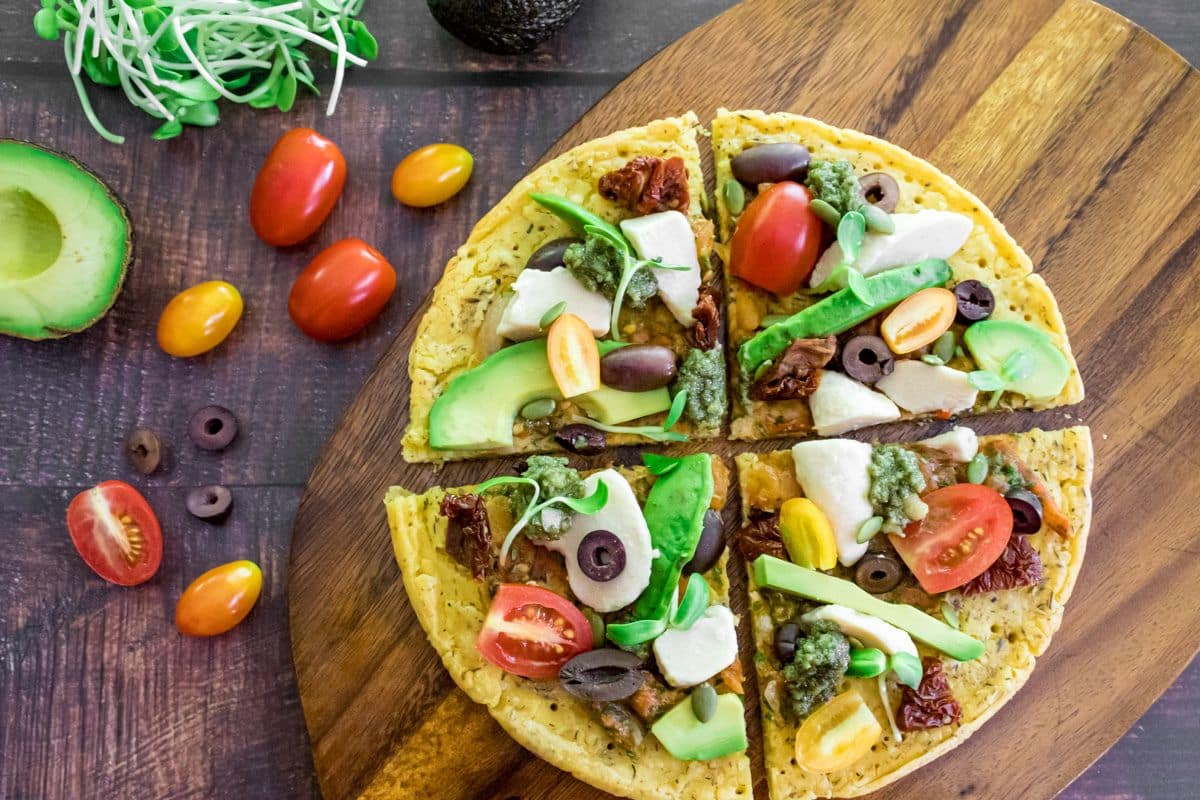 Gluten-free flatbread pizza with Mediterranean toppings served on a wooden board