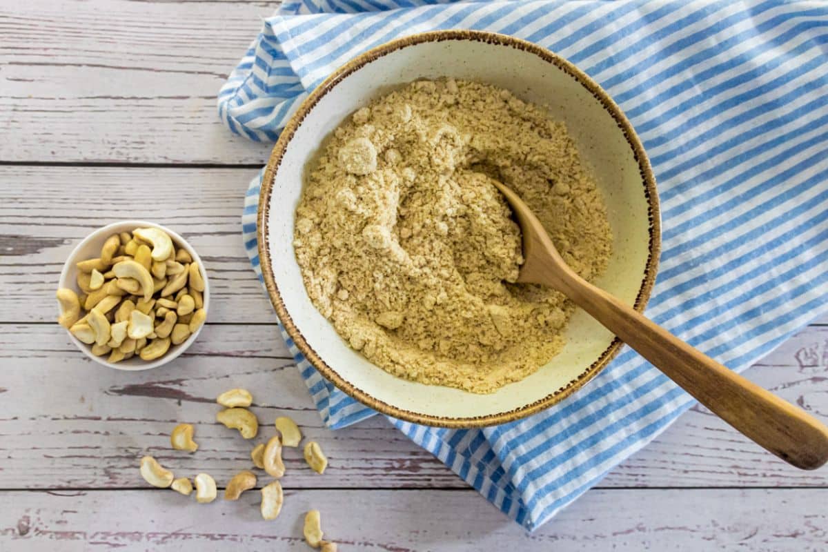vegan Parmesan cheese in a small bowl with toasted cashews and nutritional yeast.