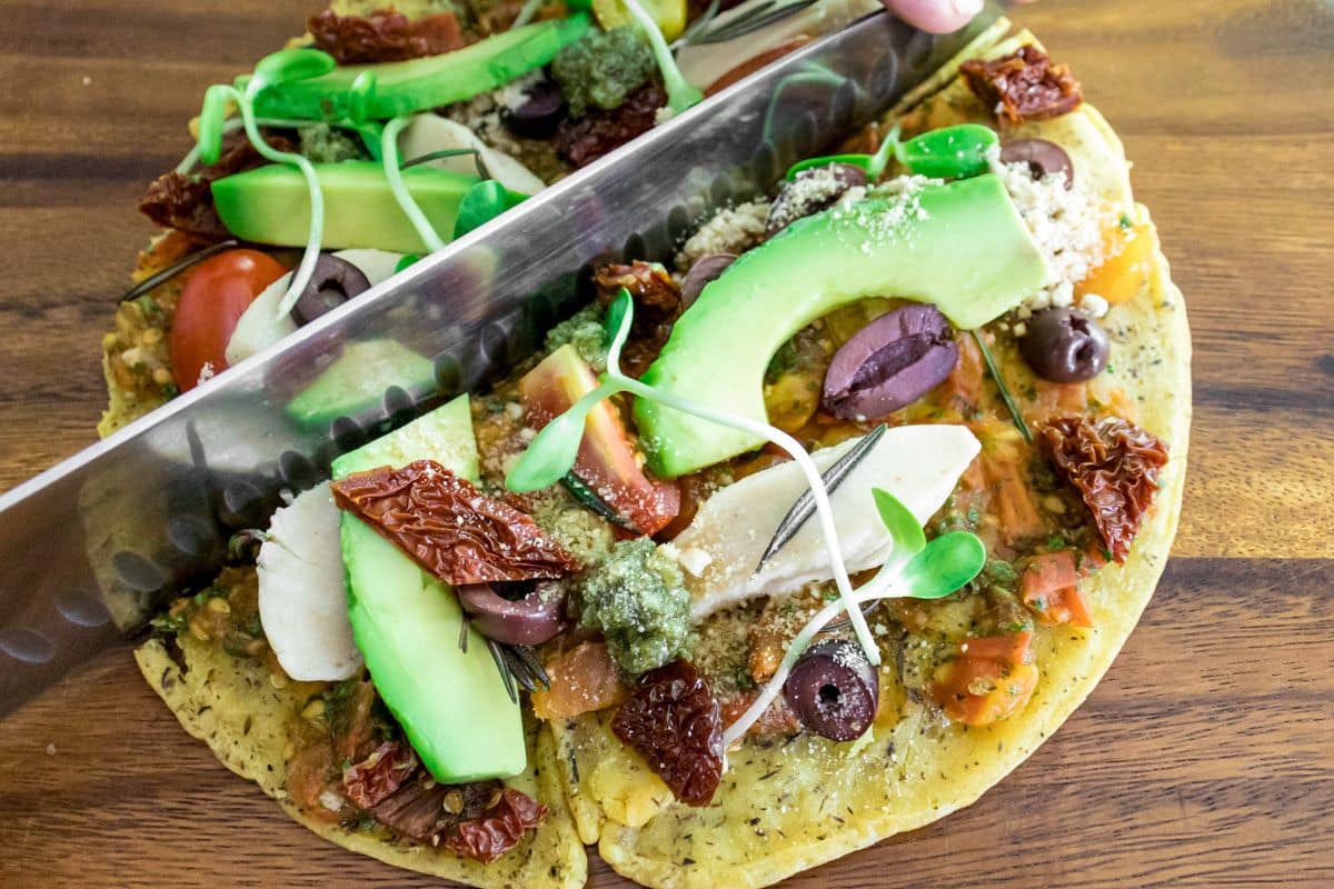 Socca-style chickpea flour pizza with sun-dried tomato tapenade, cherry tomatoes, avocado and pumpkin seeds
