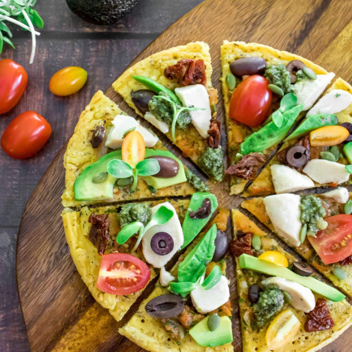 Gluten-free chickpea flatbread pizza with Mediterranean toppings served on a wooden board