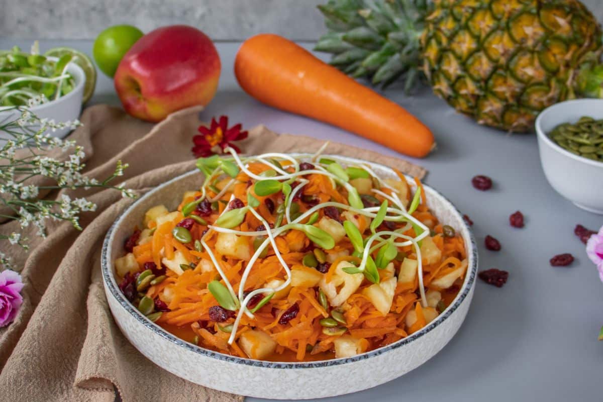 Fresh carrot pineapple salad with toasted pumpkin seeds and sunflower sprouts