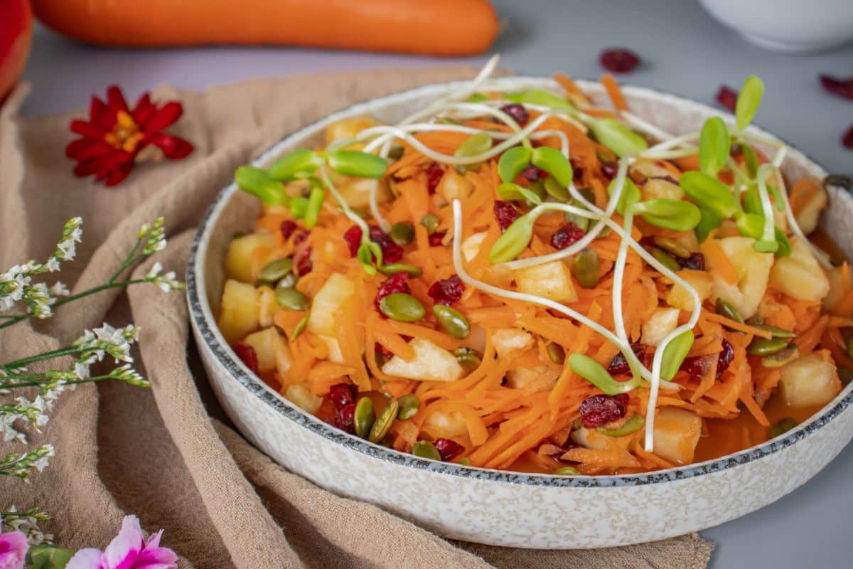 Close-up of carrot pineapple salad with sunflower sprouts and toasted pumpkin seeds