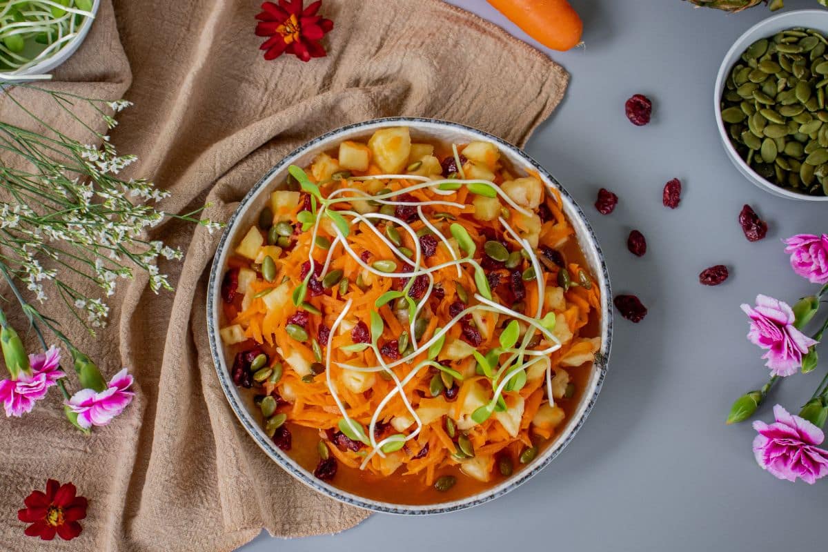 Healthy carrot salad served in a bowl with cranberries and lime
