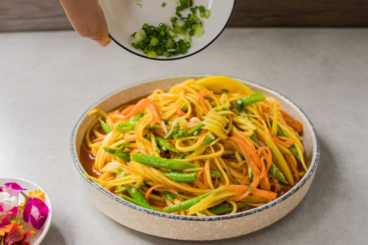 Add-spring-onion-and-edible-flowers-to-the-mango-salad