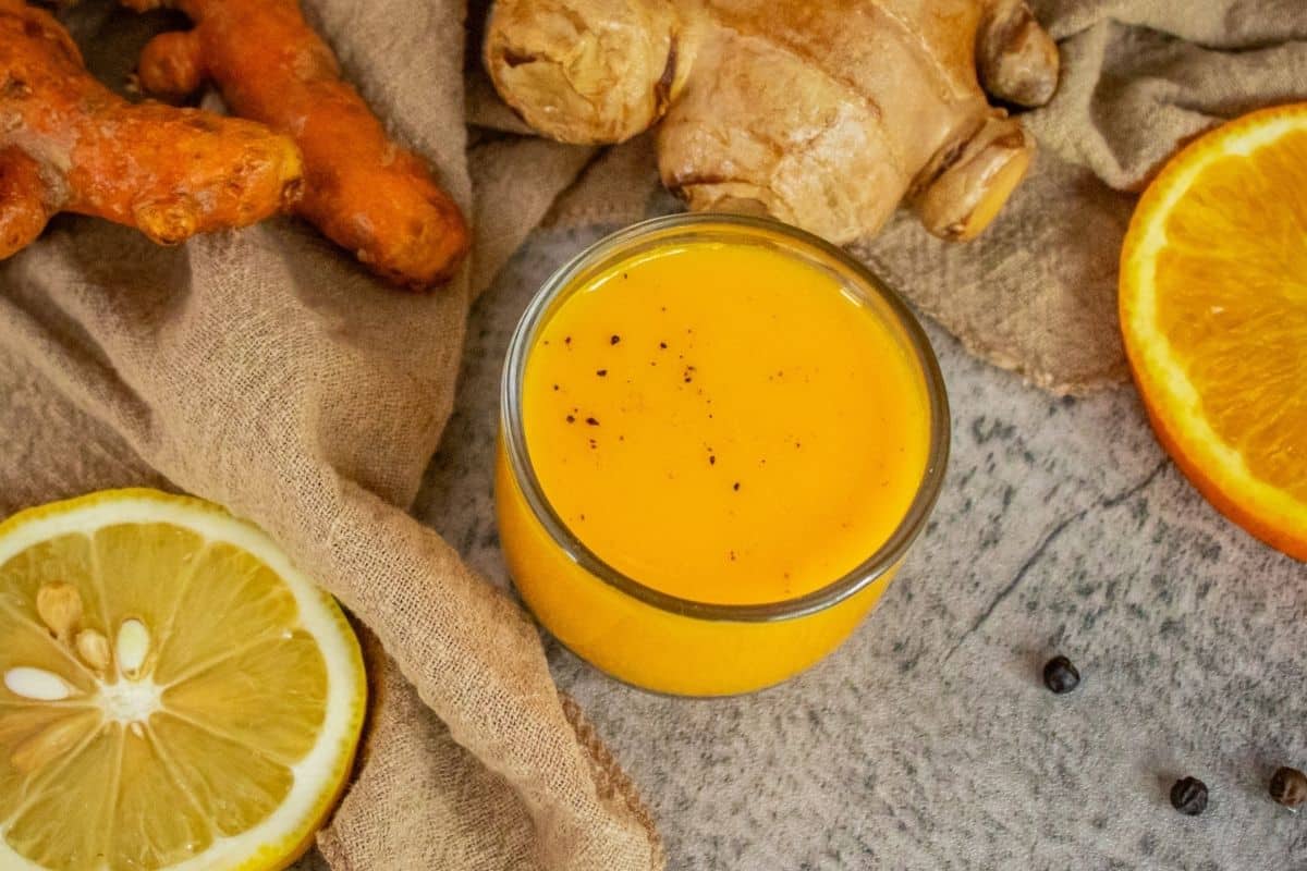 Homemade turmeric shots made with fresh turmeric, ginger, orange, lemon, carrot and black pepper.