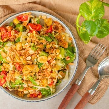 Burmese tea leaf salad (Lahpet Thoke) with fermented tea leaves, cabbage, cos lettuce, tomatoes, peanuts and crispy fava beans.