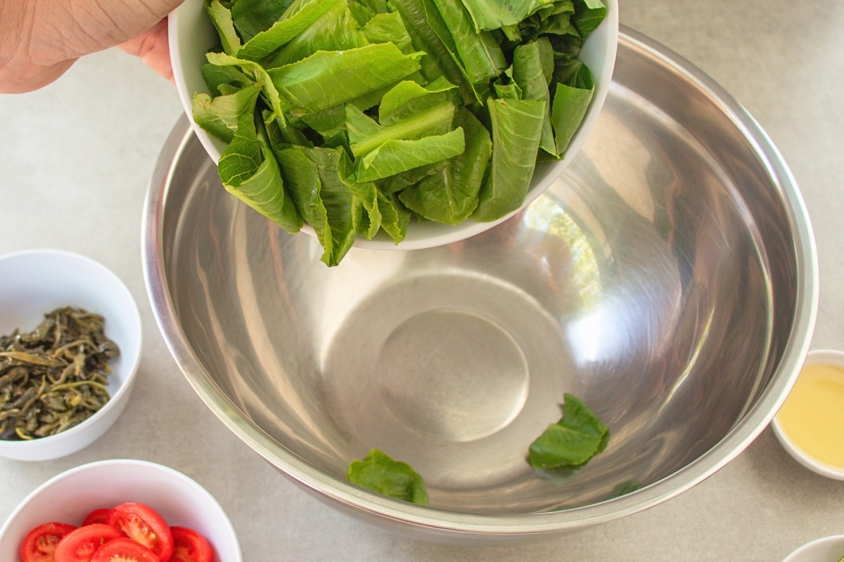 Cos lettuce added to a mixing bowl for Burmese Tea Leaf Salad