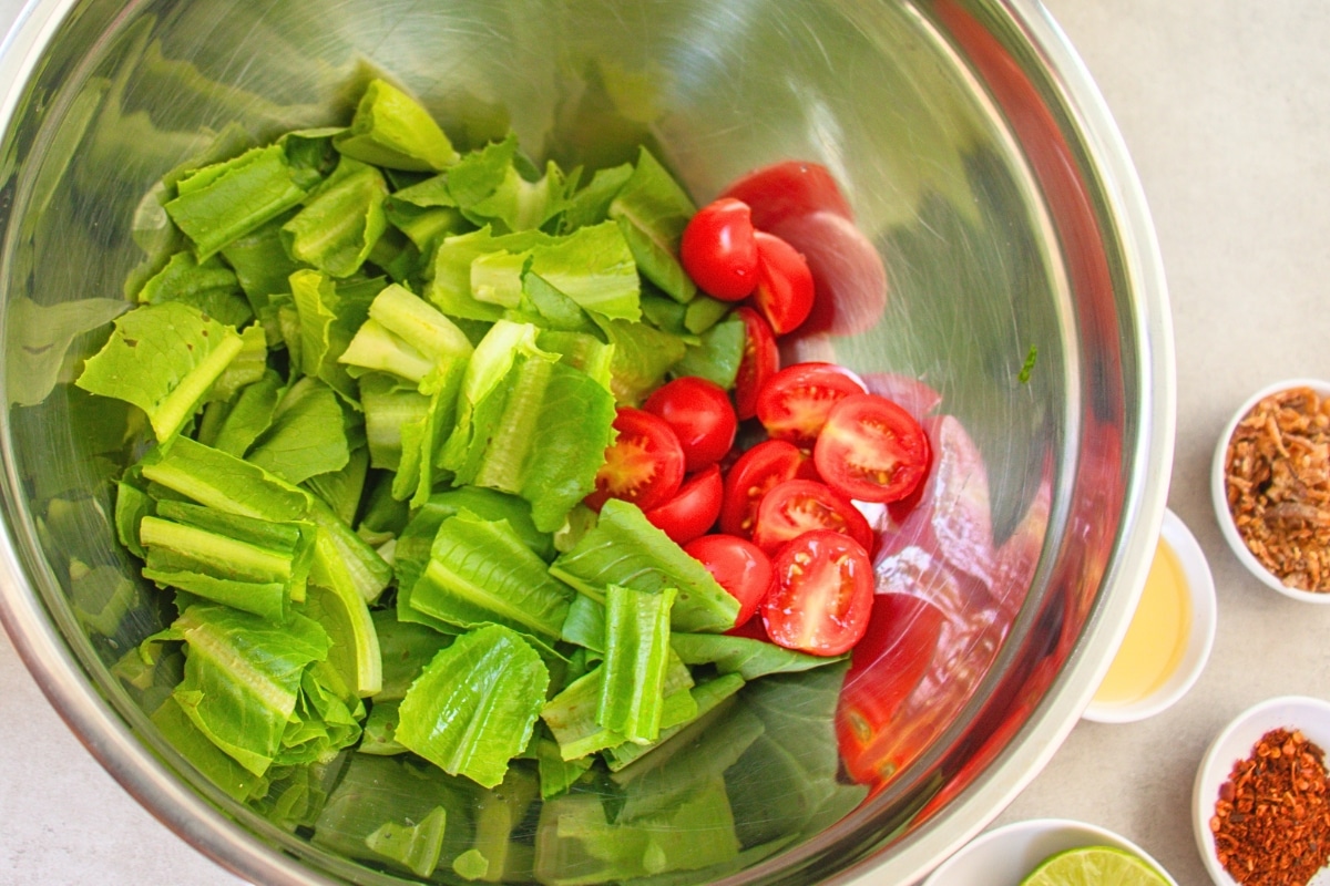 Cherry tomatoes added to the mixing bowl for Burmese Tea Leaf Salad