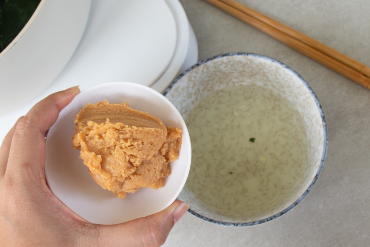 Step 8: Prepare the miso - Take a small amount of the warm broth from the pot and place it into a small bowl with the miso paste.